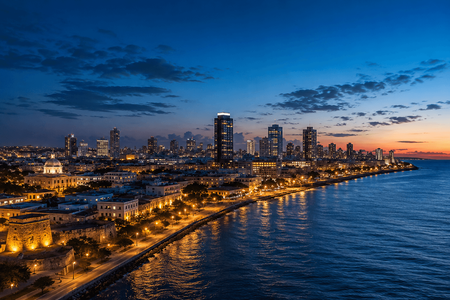 El horizonte de Santo Domingo a la hora azul, con torres comerciales modernas y el distrito colonial junto al mar Caribe.
